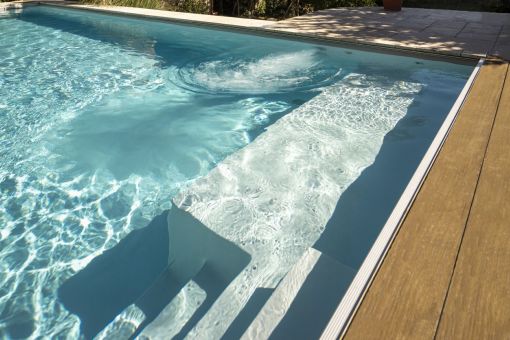 Pool mit breiter Einstiegstreppe und integrierter Massageanlage am Holzdeck